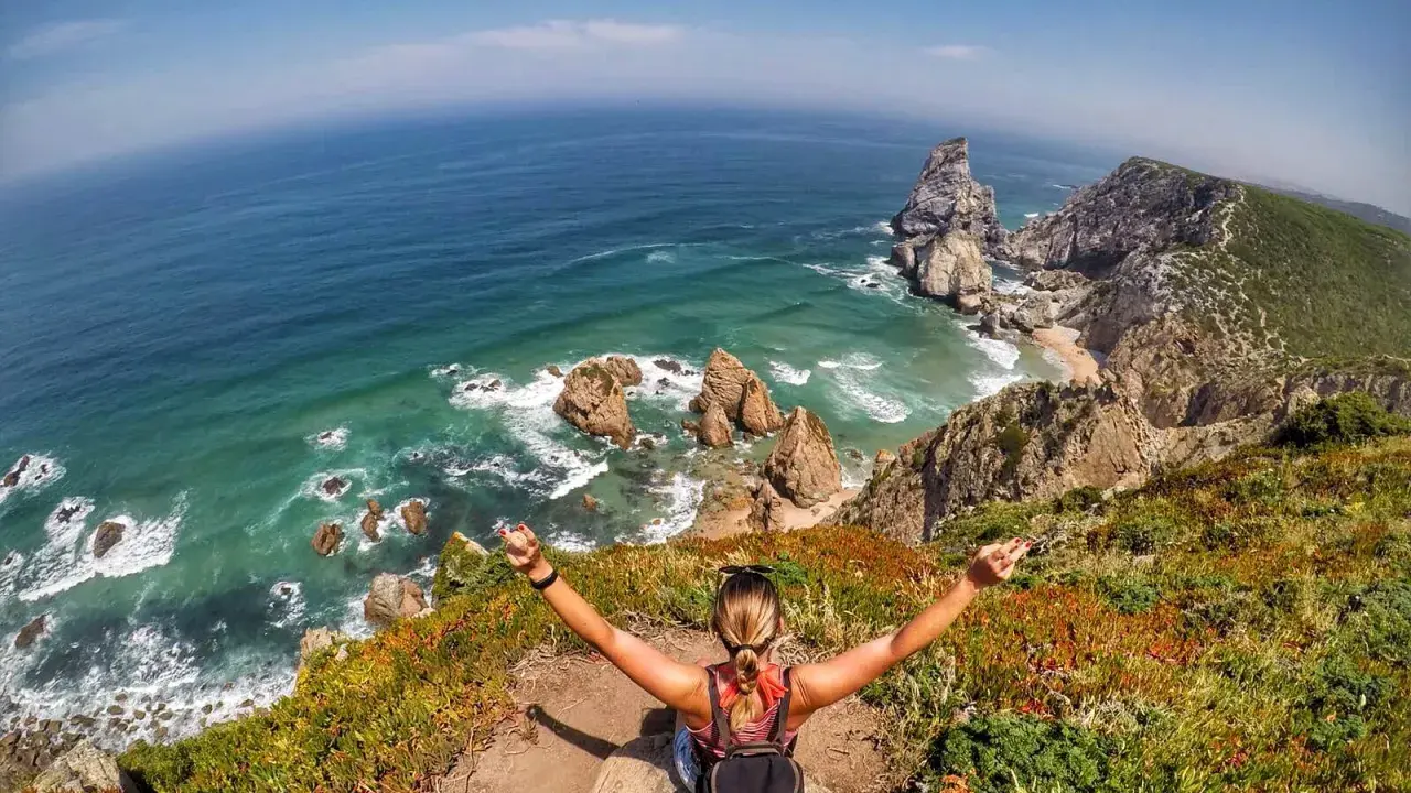 Frau genießt die atemberaubende Lissabon Natur am Cabo da Roca. Türkises Meer, Felsen und üppige Vegetation.
