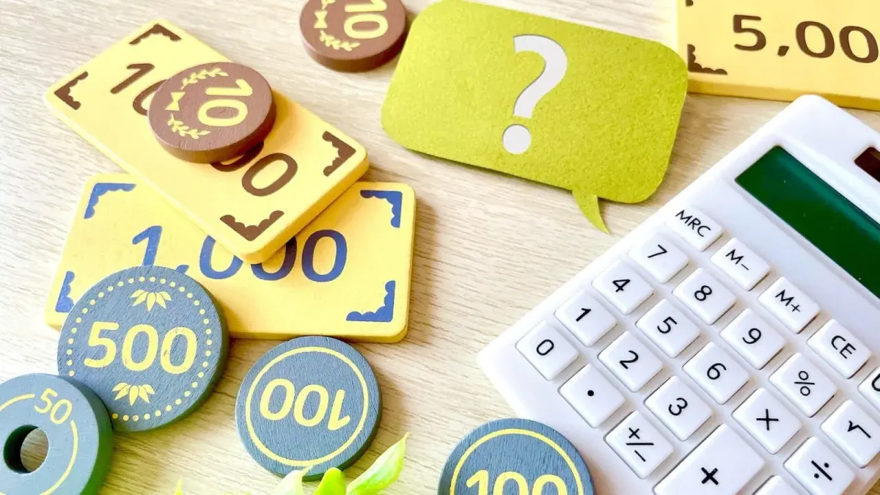 Jouets représentant des billets et des pièces, avec une calculatrice et un point d'interrogation. Une aide visuelle pour comprendre la fiscalité PEL.