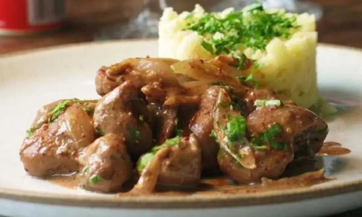 Une assiette de fricassée de rognons de veau, tendres et savoureux, accompagnés d'une purée de pommes de terre onctueuse et garnie de persil frais.