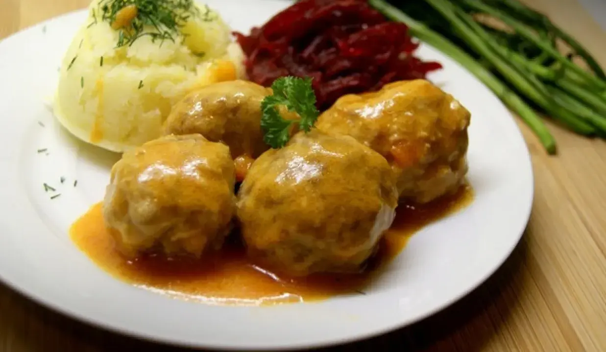 Pyszne klopsiki w sosie pomidorowym, podane z puree ziemniaczanym, buraczkami i zielonymi warzywami.