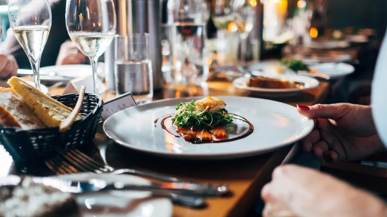 Une assiette élégante avec une spécialité du Luberon, du saumon fumé et des pousses fraîches, accompagnée de pain croustillant et de verres de vin pétillant.