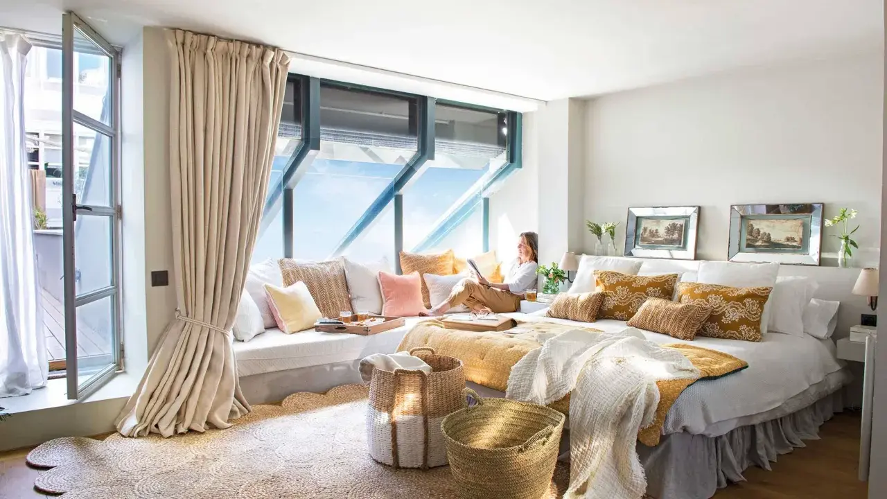 Habitación acogedora con cama grande, cojines coloridos y una zona de lectura junto a la ventana. Ideas para decorar habitacion con estilo natural.