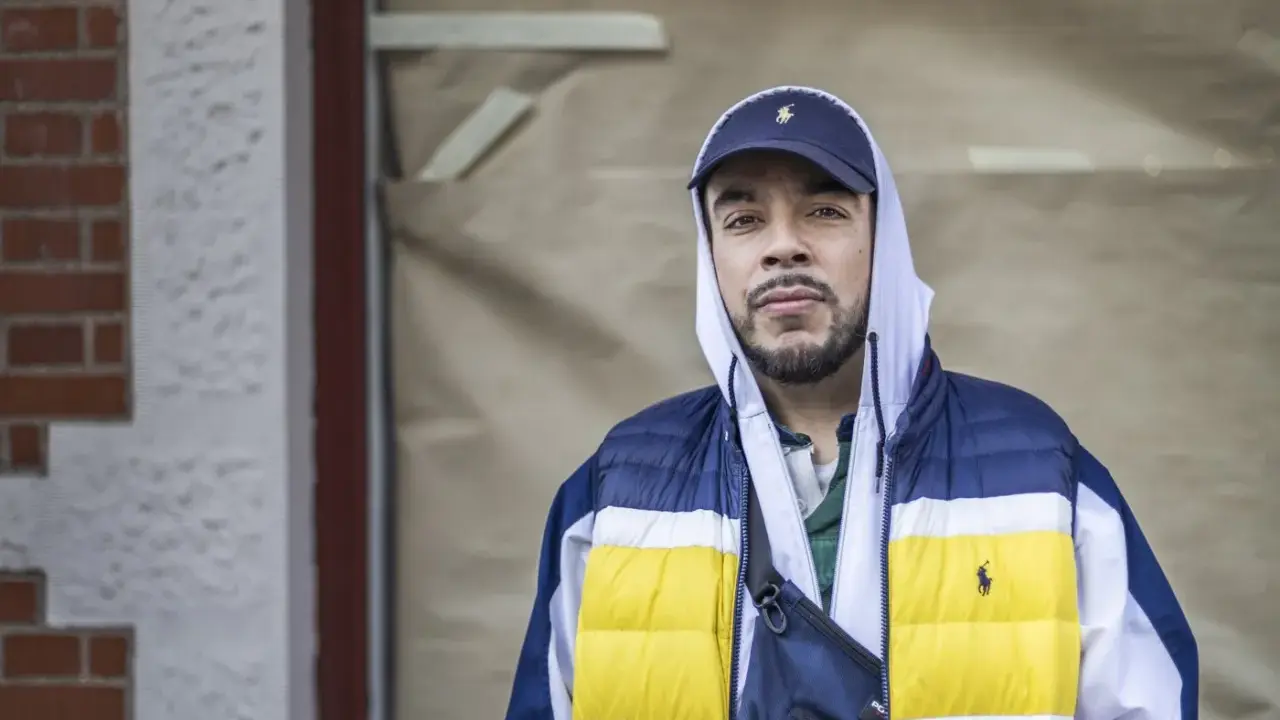 Man i hip hop style med keps och färgglad jacka.