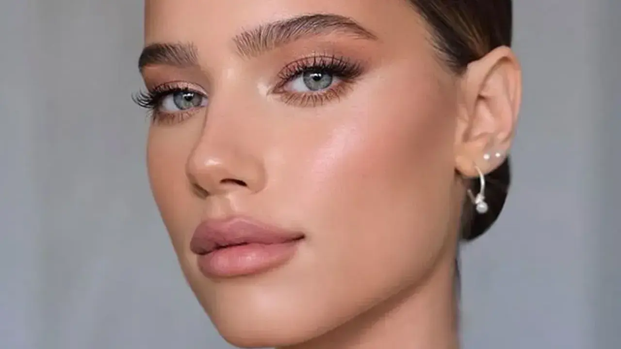 Volto femminile con trucco cerimonia impeccabile: occhi luminosi, labbra nude e pelle radiosa. Perfetto per un evento speciale.