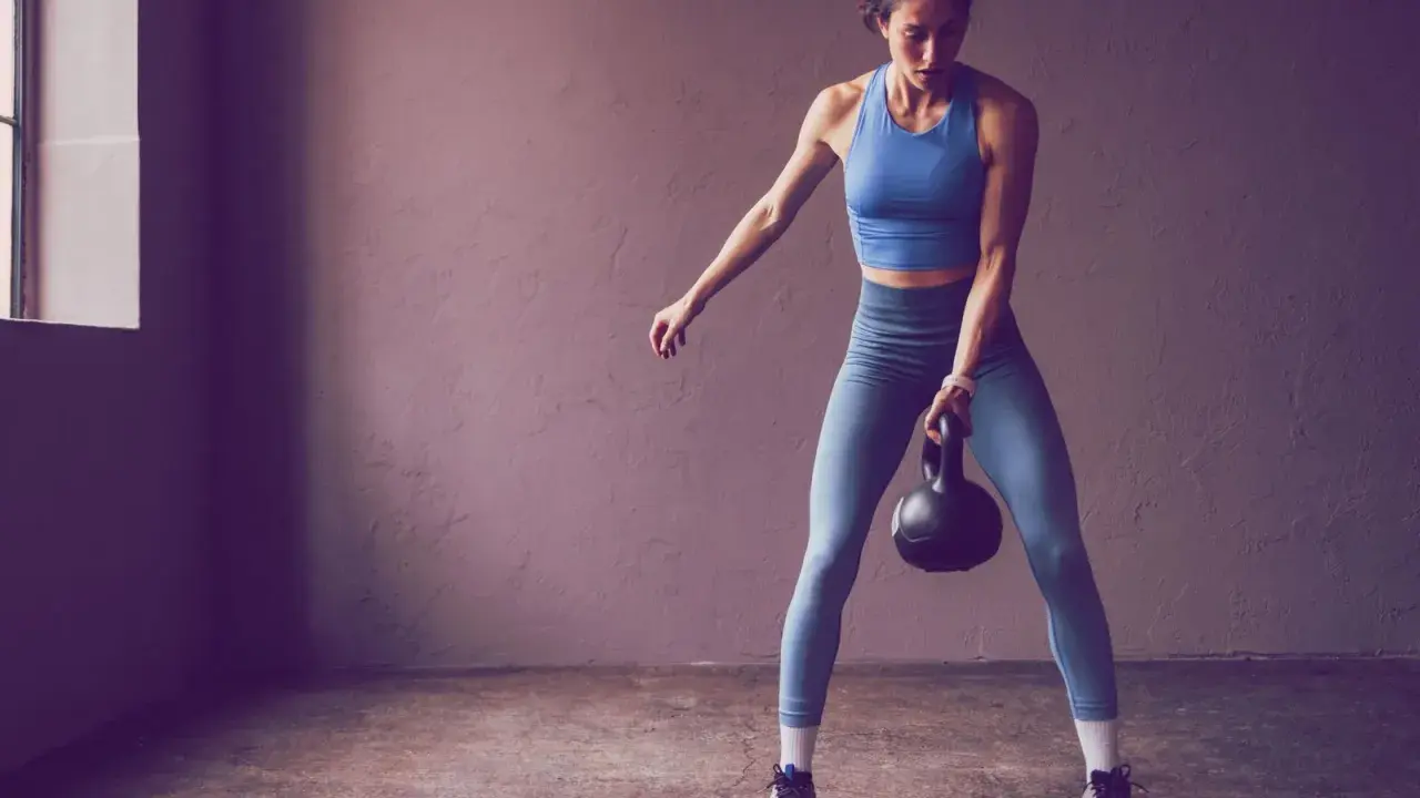 Frau trainiert mit Kettlebell, Teil der 75 Hard Challenge.