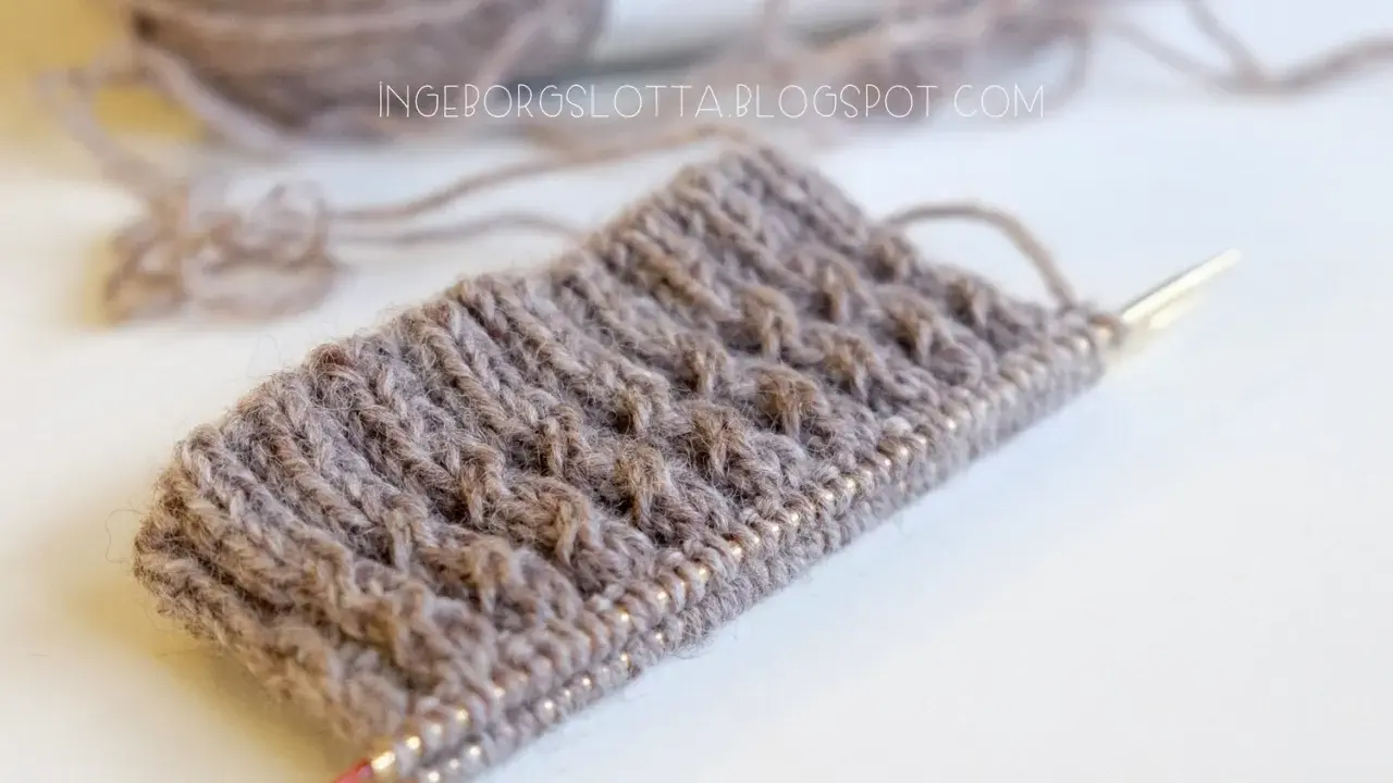 Knitted swatch with textured pattern and yarn on needles.