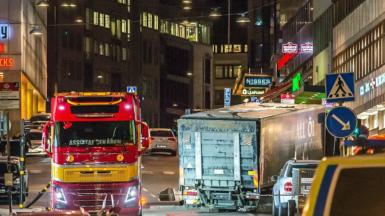 En röd bärgningsbil står vid en lastbil på Drottninggatan, en plats som för alltid är förknippad med terrordådet.