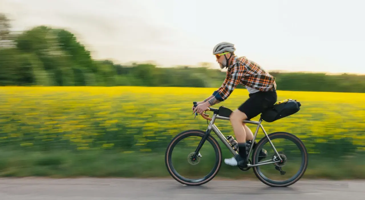 Man cyklar genom ett fält med gula blommor, en idyllisk vy över cykelleder Sverige.