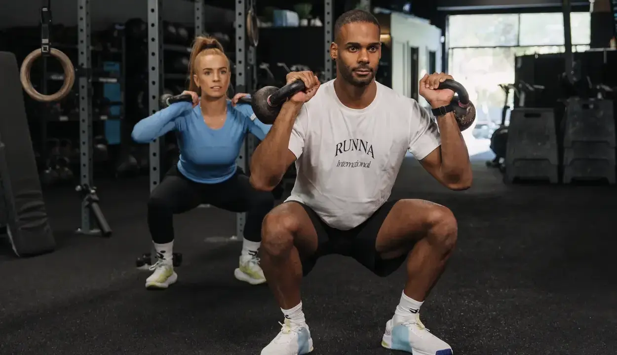 Mann und Frau trainieren Kraftsport mit Kettlebells im Fitnessstudio.