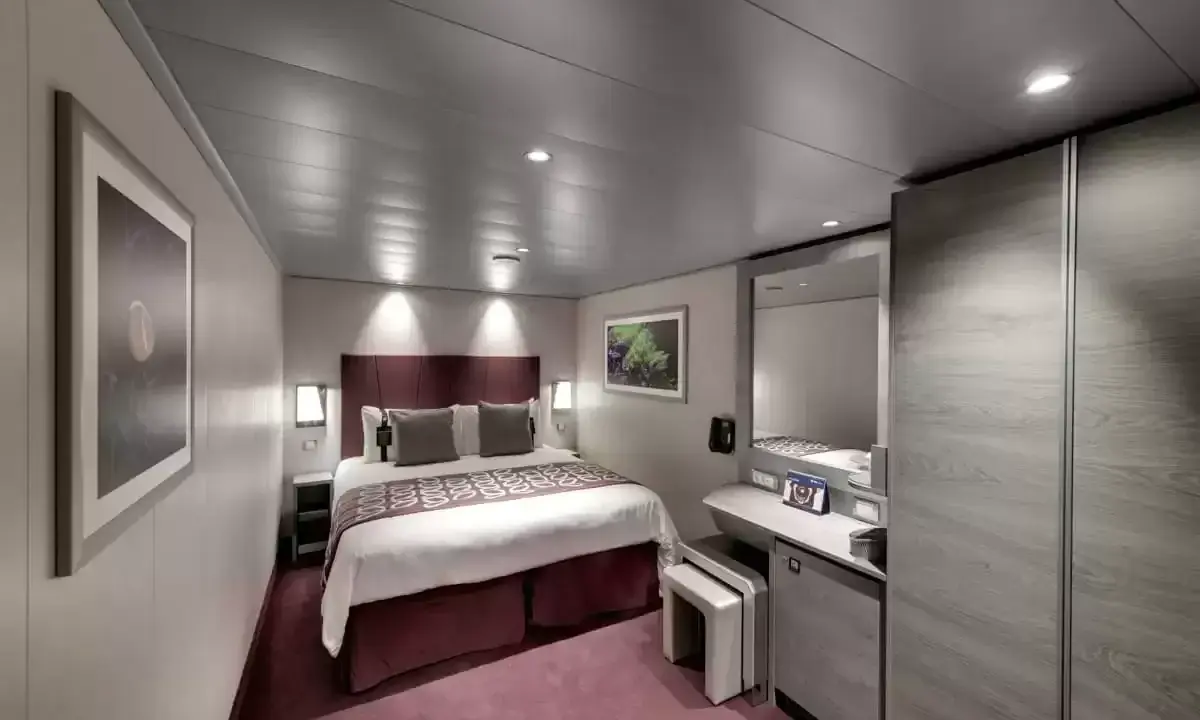 Cabina MSC Seaside, ponte 14: letto matrimoniale, specchio, armadio e un quadro decorativo.