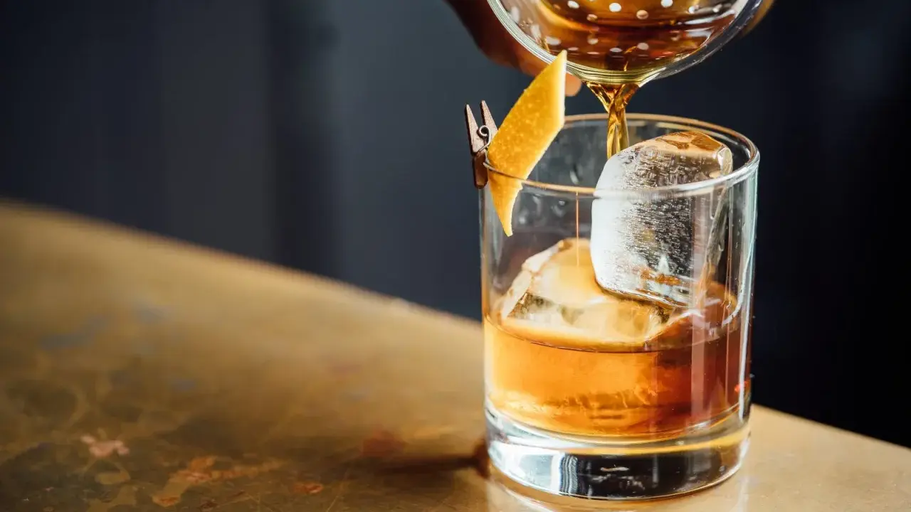 Whisky nalewana do szklanki z lodem i skórką pomarańczy.