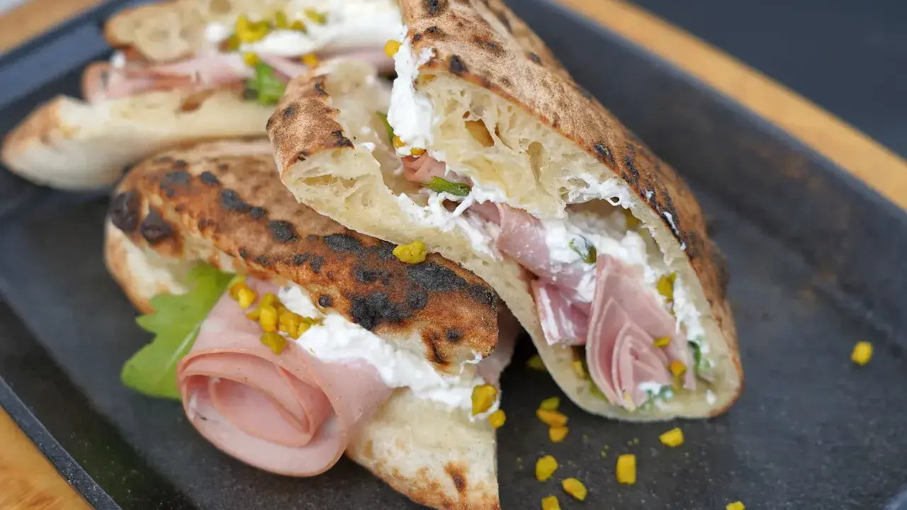 Gegrillte Pizza-Taschen gefüllt mit cremiger Ricotta, Mortadella und Pistazien.