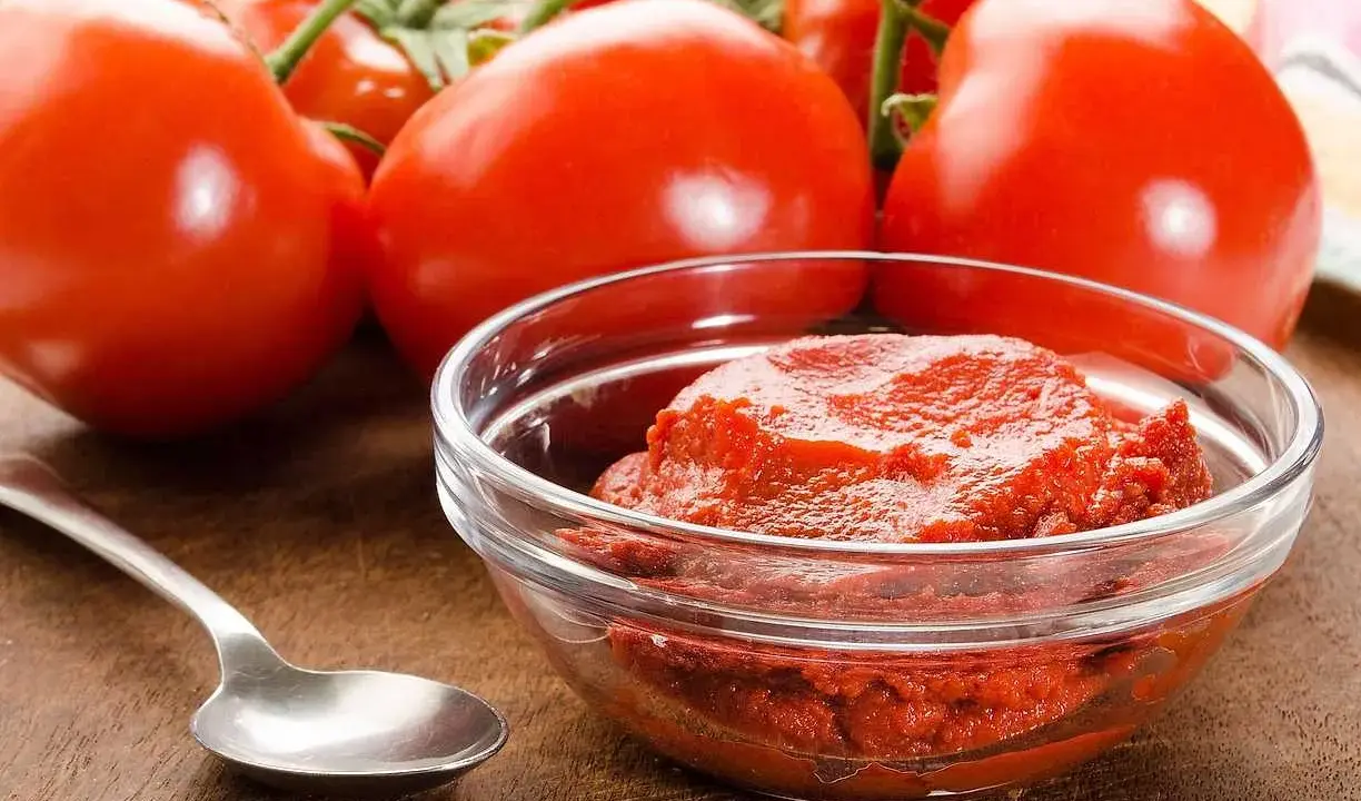 Färska tomater och en skål med tomatpuré, perfekt för ditt tomatpuré recept.