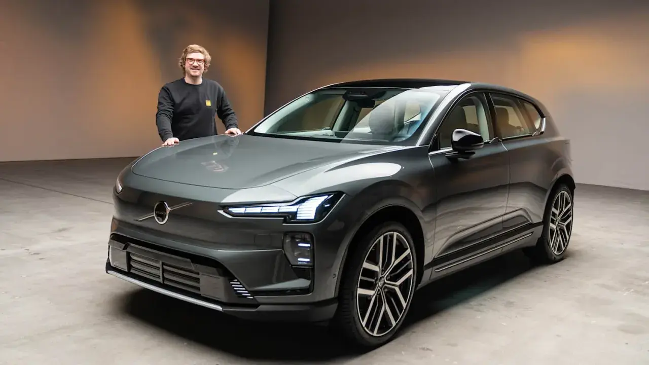 Ein Mann steht neben einem modernen, grauen Volvo EX90.