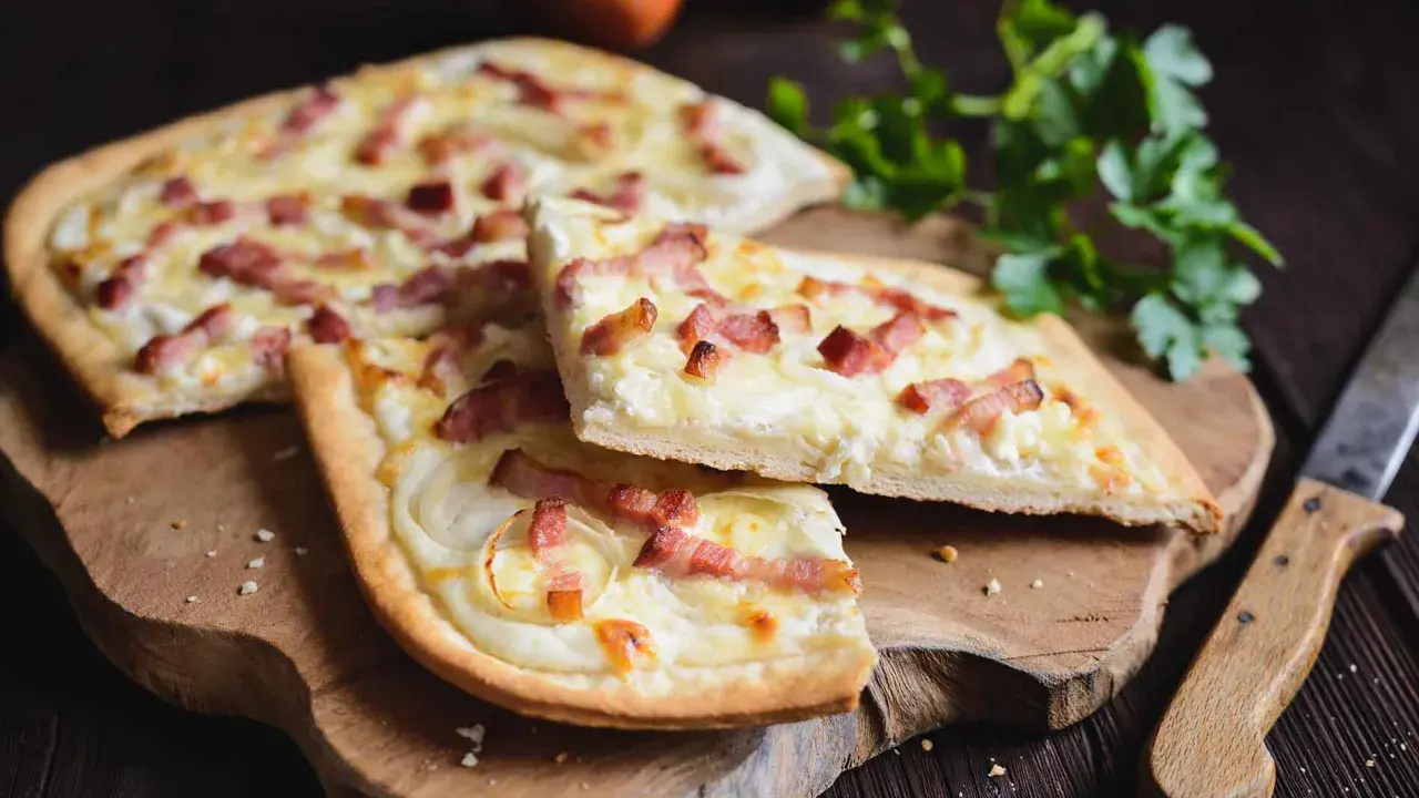 Flammekueche, une spécialité alsacienne d'origine, garnie de lardons et d'oignons sur une pâte fine.