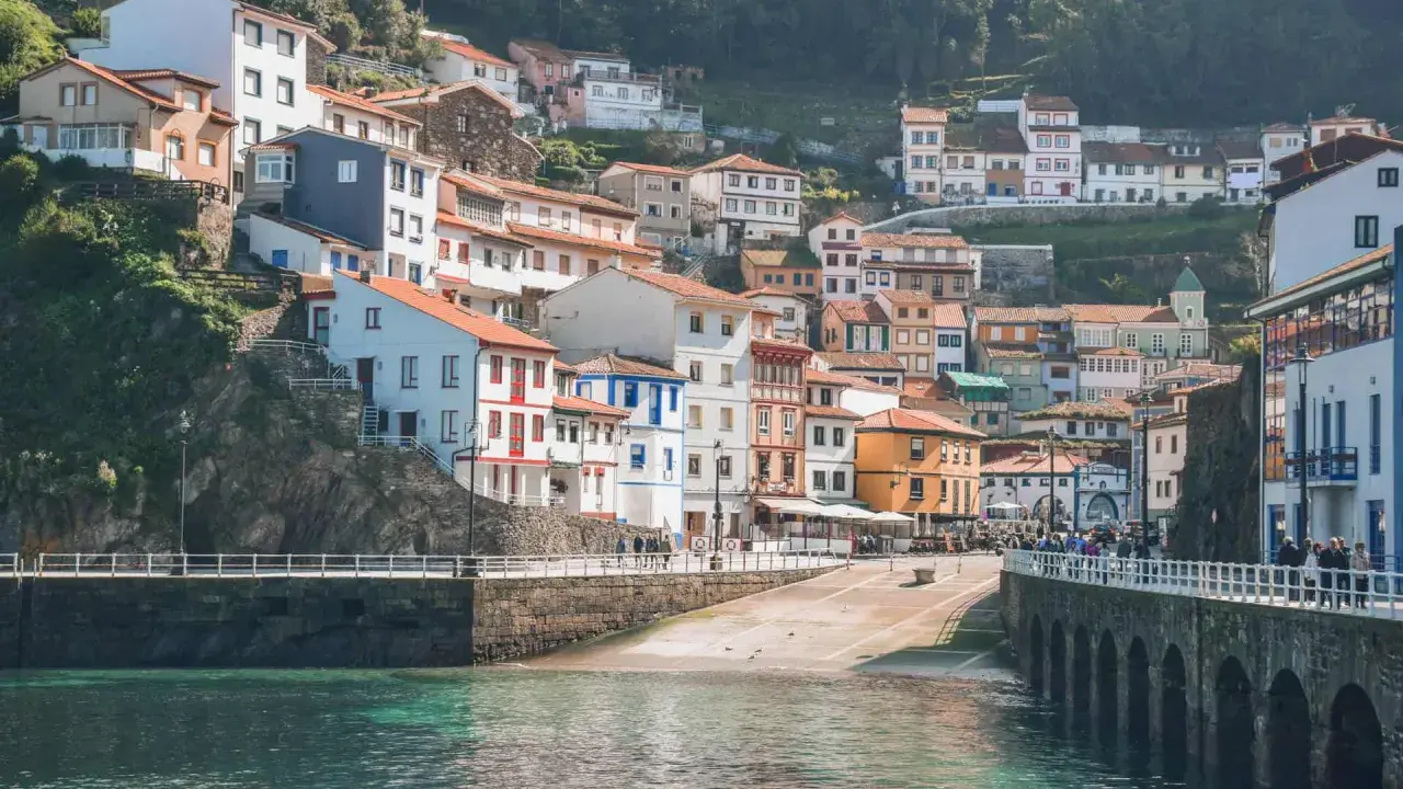 Casas de colores se aferran a la ladera en uno de los pueblos con encanto en Asturias, con el mar turquesa al frente.