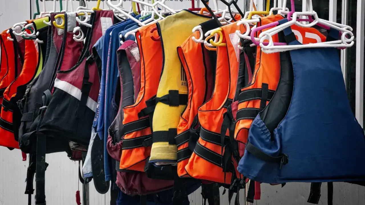 Chalecos salvavidas de varios colores, como naranja, amarillo y azul, colgados en perchas. Listos para la aventura, estos chalecos son de epis categoria 2.