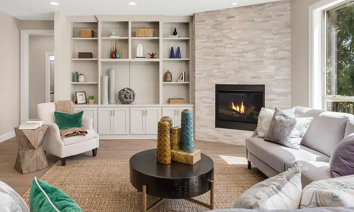 Un elegante mueble salones con chimenea de piedra, estanterías repletas de objetos decorativos y cómodos sofás.