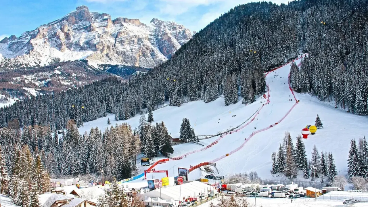 Ośnieżony stok narciarski w Alta Badia z lasem i górami w tle.