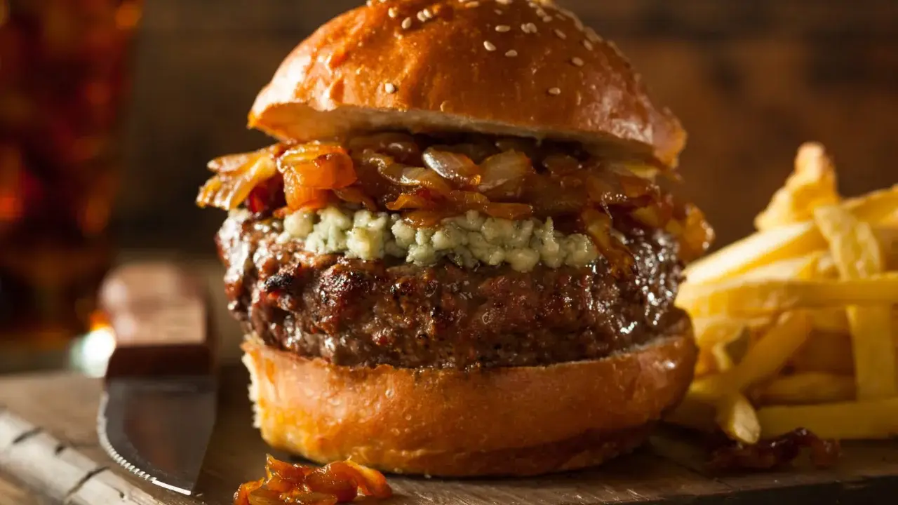 Jugosa hamburguesa con queso de cabra desmenuzado, cebolla caramelizada y papas fritas crujientes.