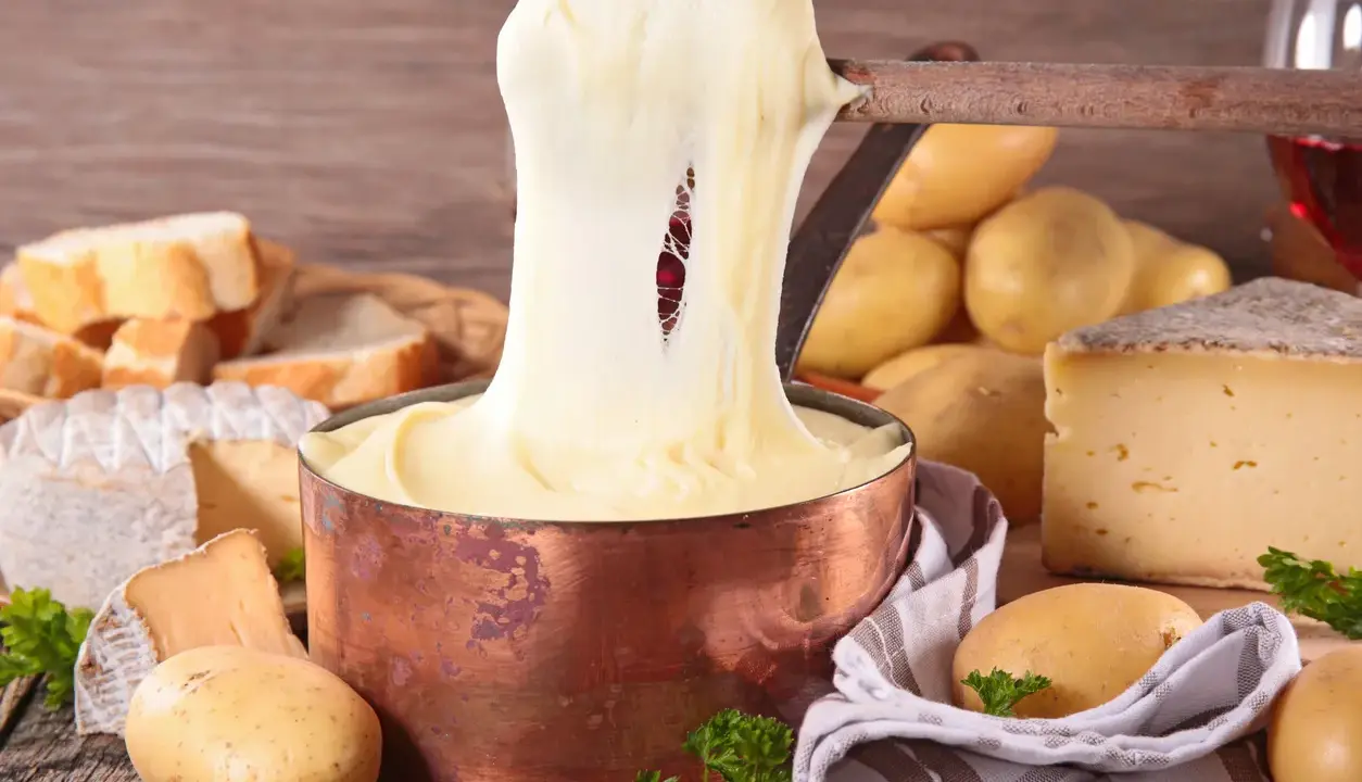 Fondue au fromage, un délice des spécialités culinaires auvergnates, avec du pain, des pommes de terre et du vin rouge.