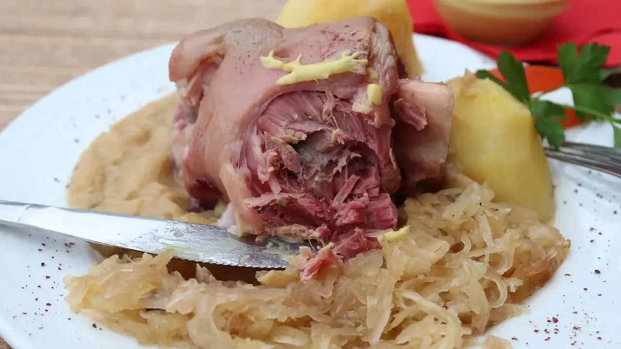 Un plat copieux de spécialités culinaires alsaciennes : jarret de porc, purée de pommes de terre et choucroute, garni de moutarde.