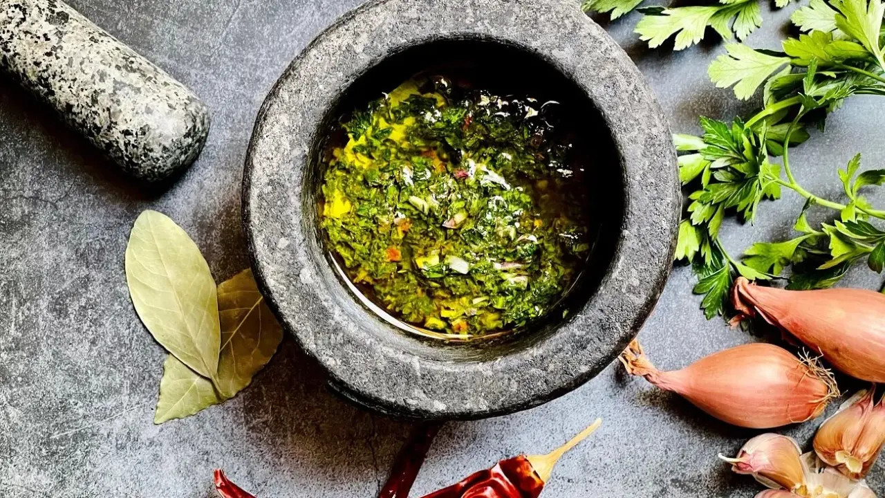 Frische Kräuter, Knoblauch, Schalotten und Chili – die chimichurri hauptzutaten werden im Mörser zubereitet.