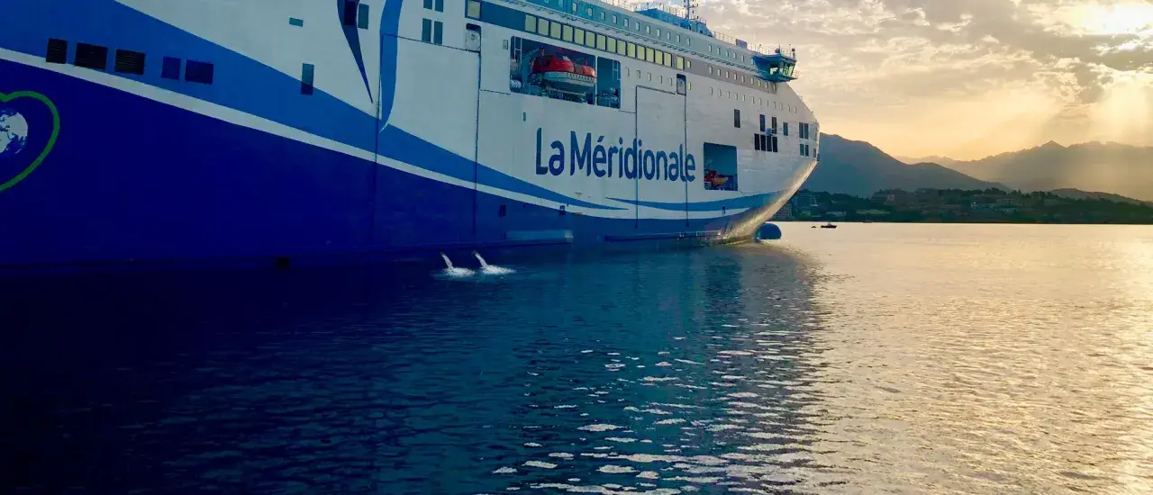 Le ferry "La Méridionale" se prépare à partir, le ballast navire est ajusté pour la traversée. L'eau reflète le ciel doré.