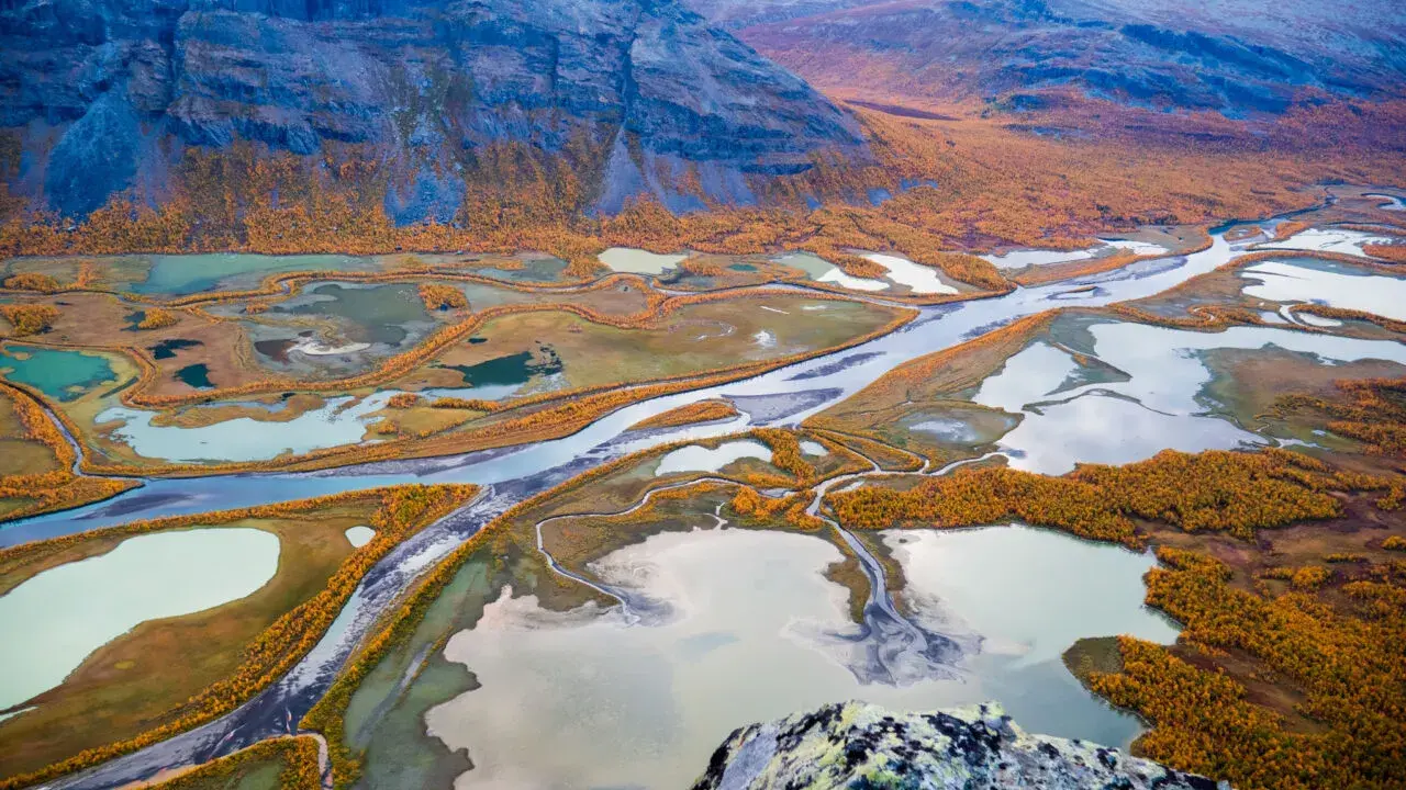 Vacker höstfärgad vy över Kungsleden, med slingrande vattendrag och fjäll. Perfekt tid att vandra.