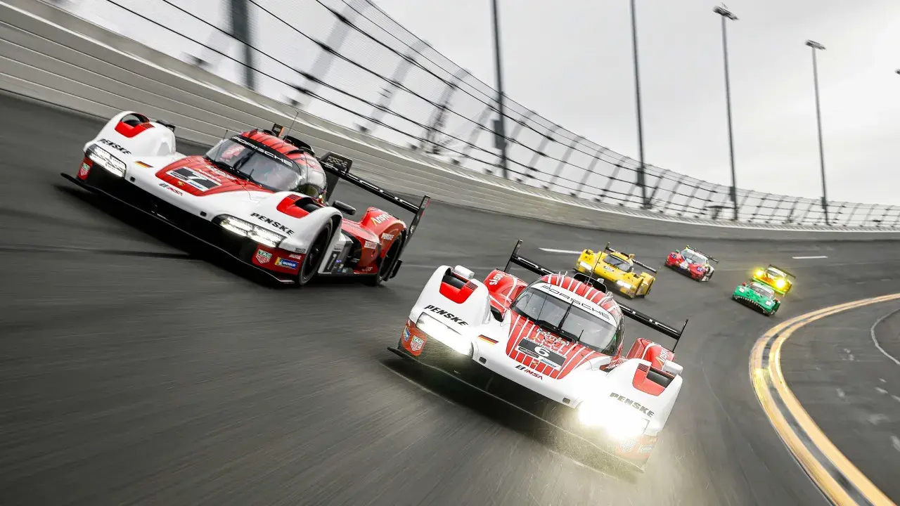 Mehrere Rennwagen, darunter ein weiß-roter Porsche, rasen auf der Strecke des 24-Stunden-Rennens von Daytona.