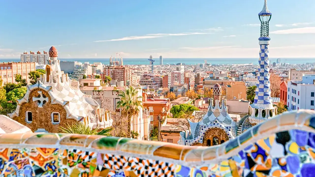 Kolorowe mozaiki i bajkowe budowle w Parku Güell z widokiem na Barcelonę.