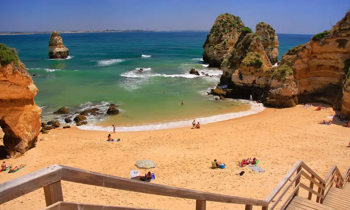 Sonnige Bucht mit goldenem Sand und Felsformationen. Ein perfekter Ort für einen entspannten Tag am Meer, nur eine kurze Fahrt vom Flughafen Portugal Algarve entfernt.