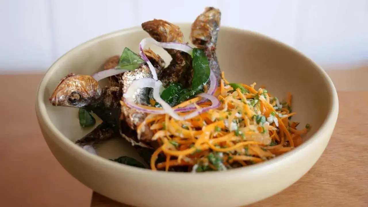 Poisson frit croustillant avec salade de carottes râpées et oignons rouges, une spécialité du restaurant la joie.