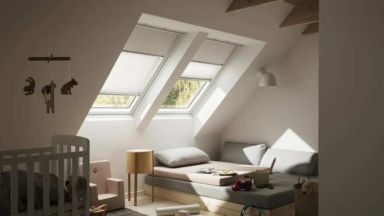 Habitación infantil con dos ventanas de tejado equipadas con cortinas para Velux caseras, cama baja, cuna y juguetes.