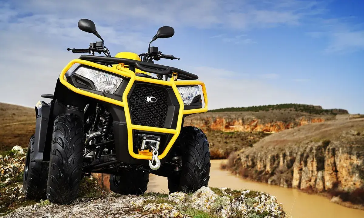 Un quad amarillo listo para conducir por terrenos escarpados junto a un río.