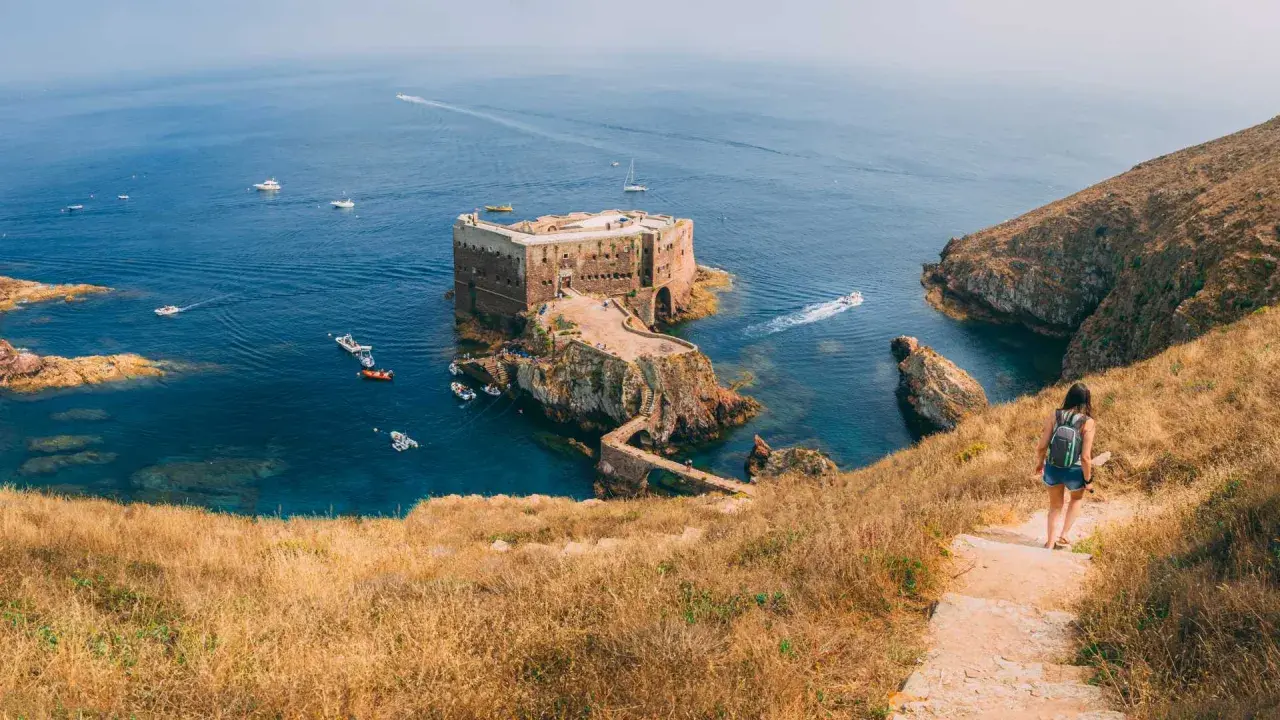 Wanderin auf der Insel Berlenga Grande, Portugal, Leiria. Eine Festung thront im Meer, Boote schaukeln im Wasser.