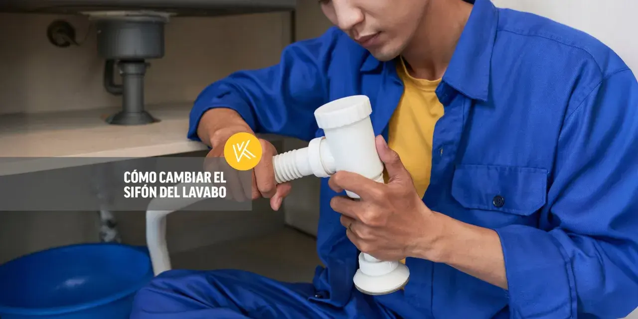 Un fontanero realiza la instalación del sifón del lavabo, sujetando la pieza blanca con ambas manos.