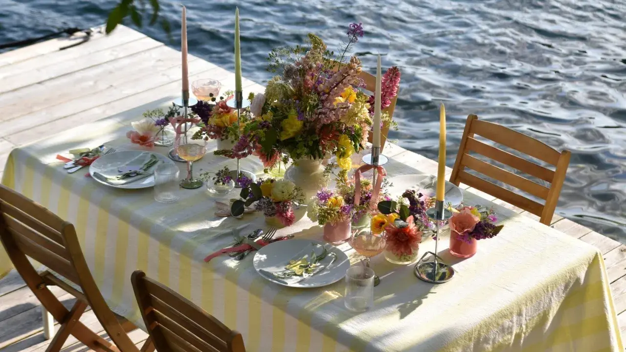 Enkel dukning vid vattnet med blommor och ljus.