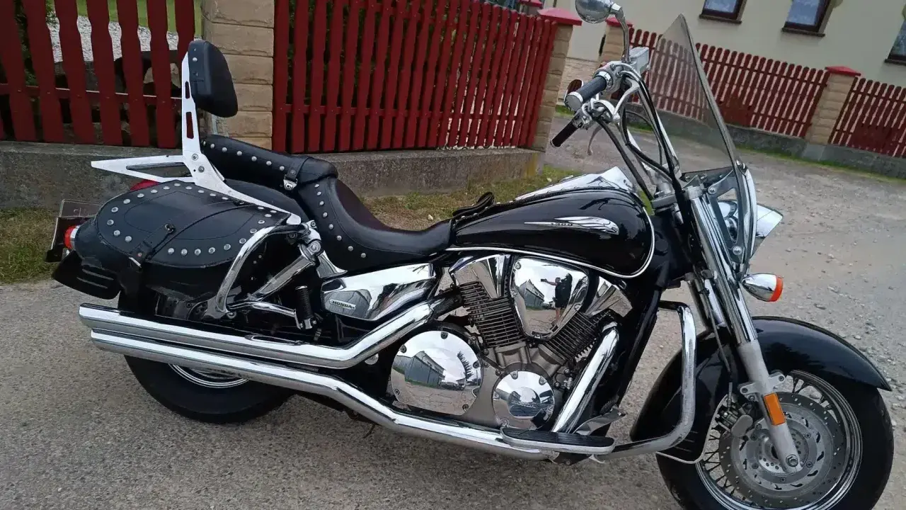Błyszczący, czarny motocykl Honda VTX 1300 z sakwami i oparciem. Dane techniczne tego klasyka są imponujące.