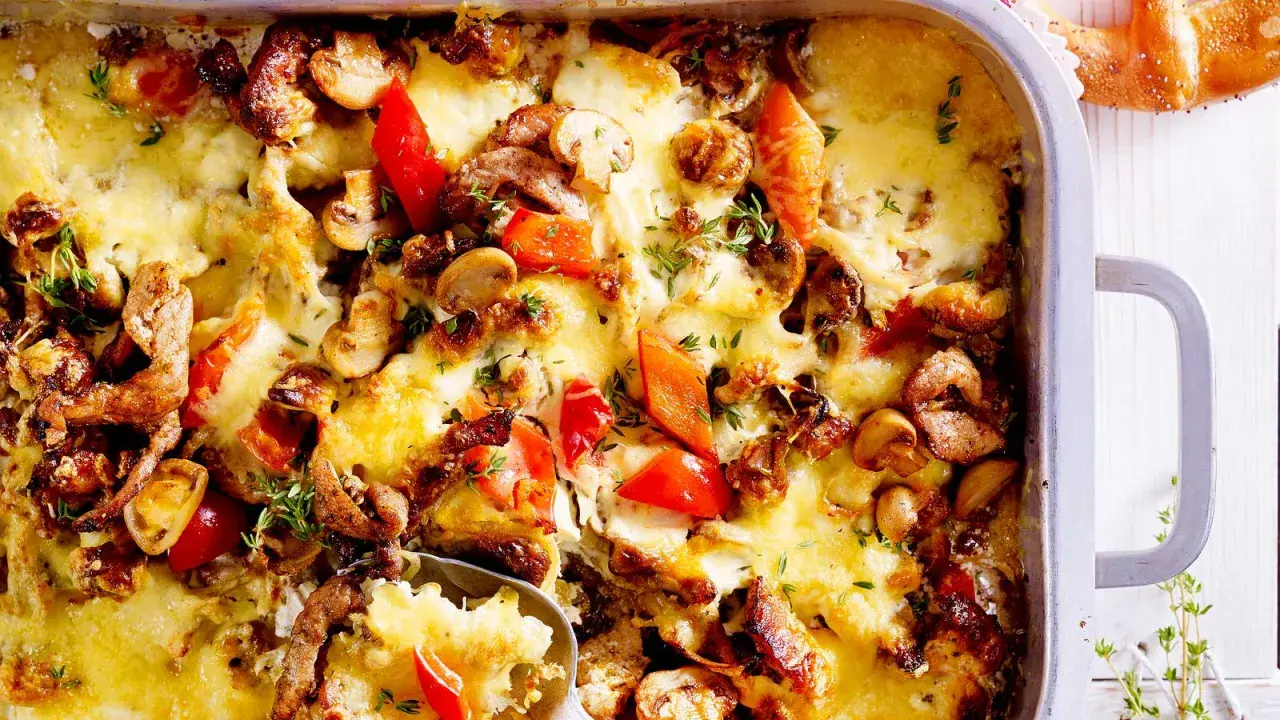 Herzhafter Gyros Auflauf mit geschmolzenem Käse, Pilzen und Paprika, garniert mit frischen Kräutern.