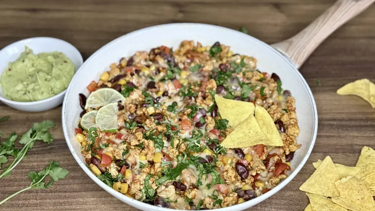 Pyszny kurczak po meksykańsku z fasolą, kukurydzą i serem, podany z guacamole i nachos.