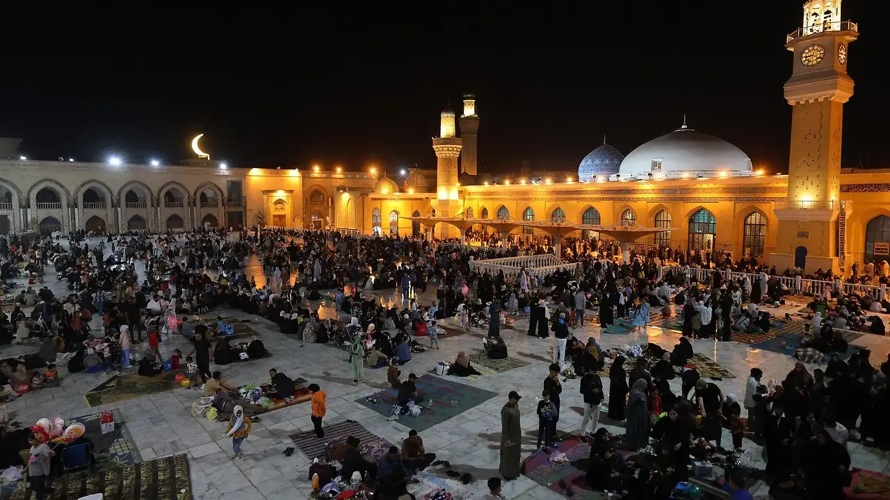 Menschen versammeln sich nachts auf einem Platz vor einer Moschee, um die Qadr Nacht zu begehen.