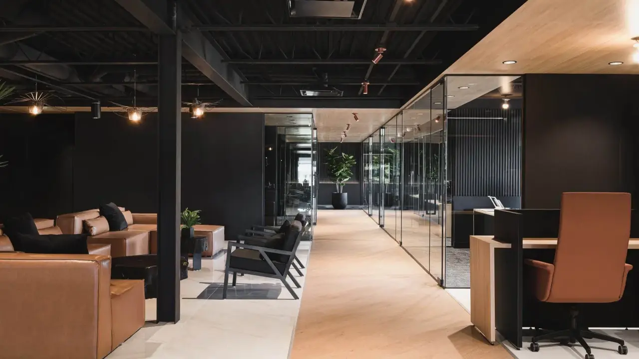 Un espace de travail innovant avec des canapés en cuir, des chaises modernes et des bureaux vitrés.