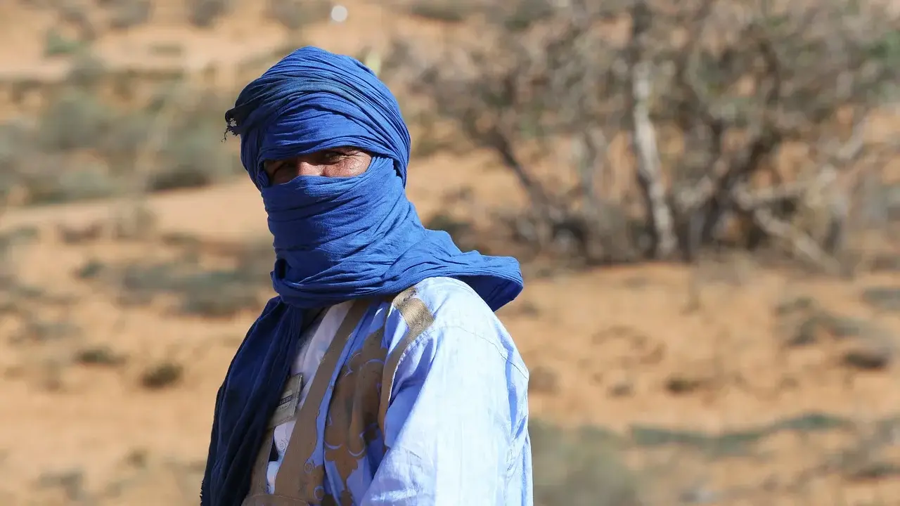 Ein Mann in traditioneller blauer Kleidung und Turban blickt aus der Wüste. Sind Marokkaner Araber? Ja, viele Marokkaner sind Araber.