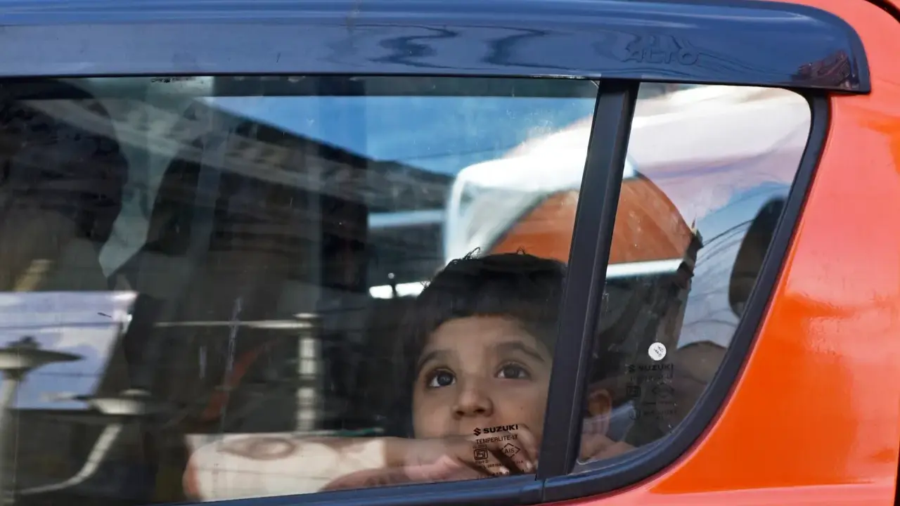 Niño mira por la ventana del coche, apoyado en el cristal, sin silla en el coche. Reflejos en el vidrio.
