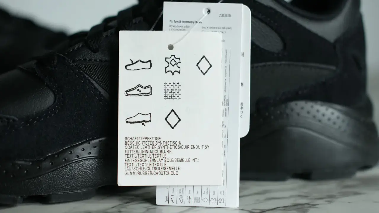 Czarna cholewka w adidasach, wykonana z połączenia skóry i materiałów syntetycznych, z widoczną metką z symbolami pielęgnacji.