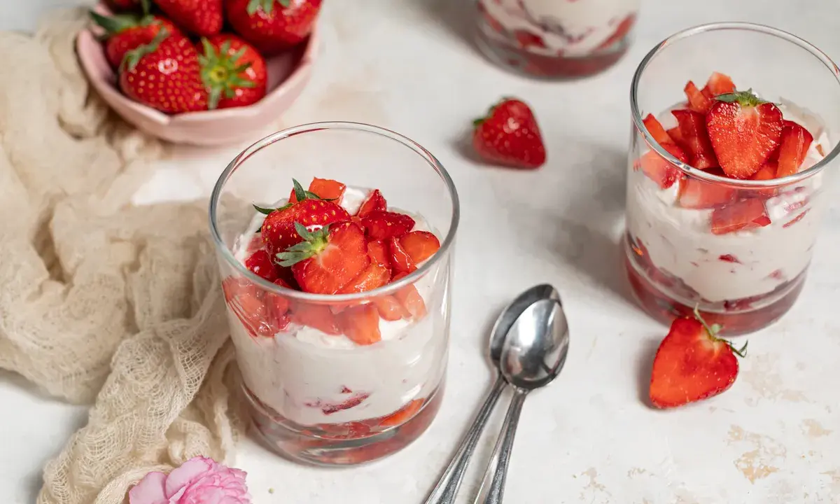 Erfrischendes Erdbeer Quark Dessert in Gläsern, garniert mit frischen Erdbeeren. Ein leichter Genuss für warme Tage.