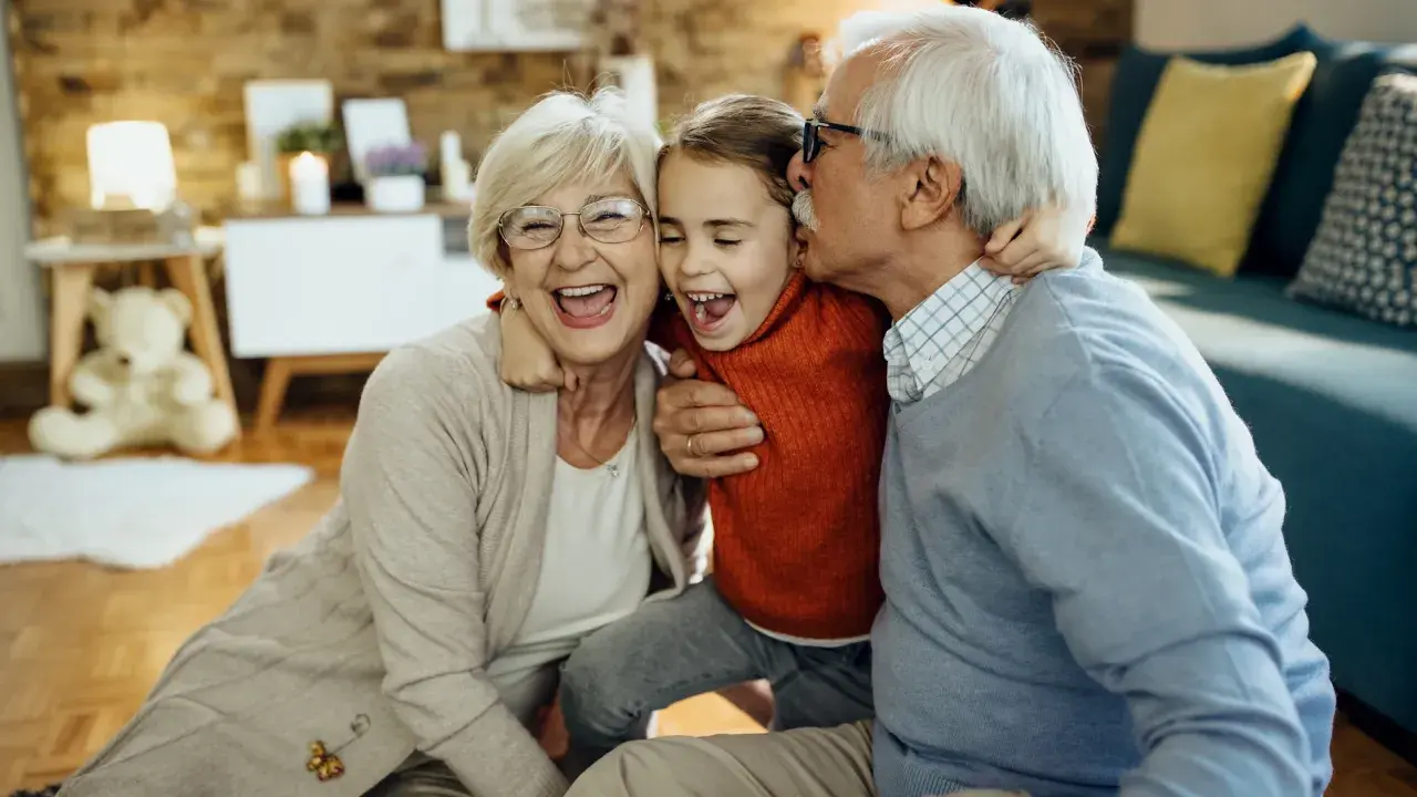 Abuelos riendo y abrazando a su nieta. Un momento tierno que demuestra la alegría de los padres que dejan a sus hijos con los abuelos.