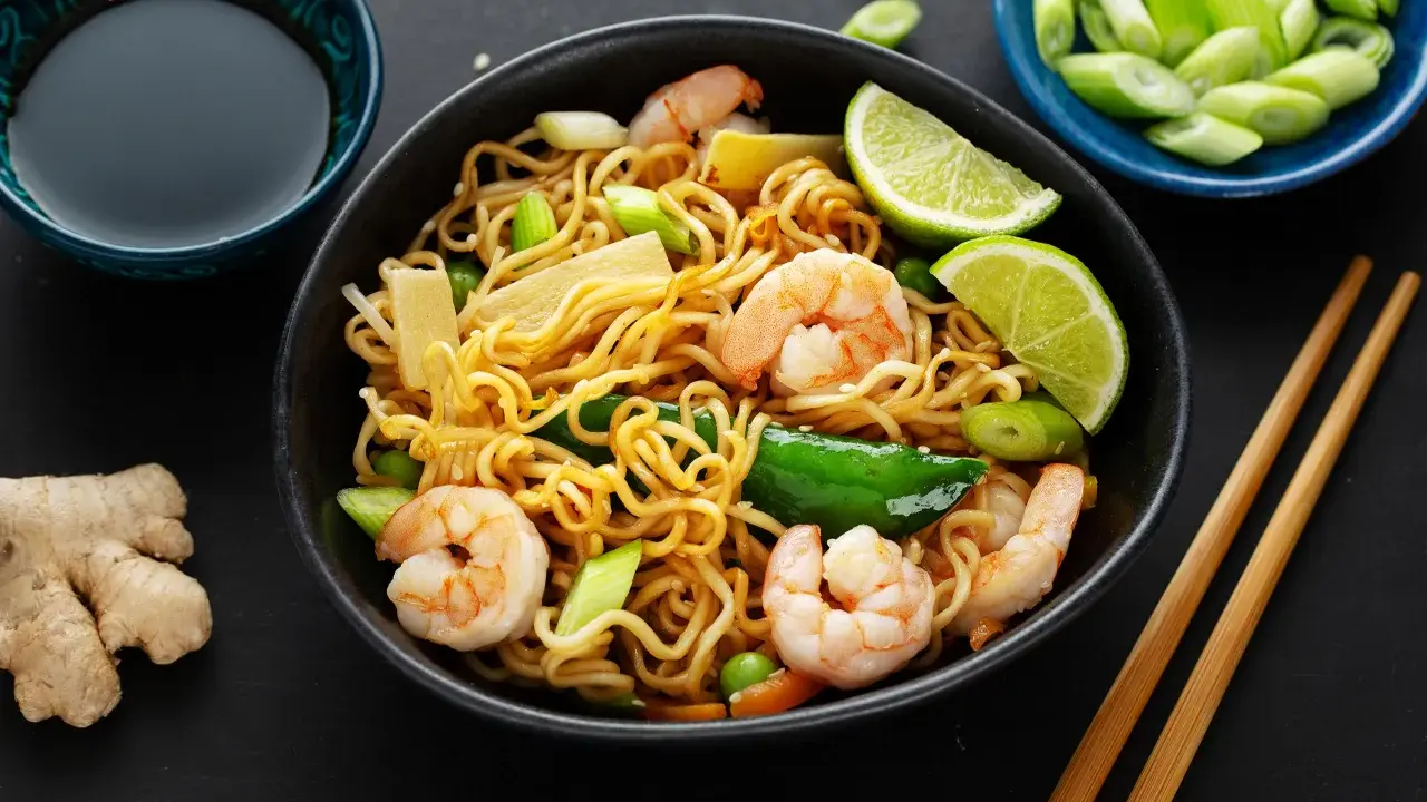 Makaron chow mein z krewetkami, warzywami i limonką, podany z sosem sojowym i imbirem.