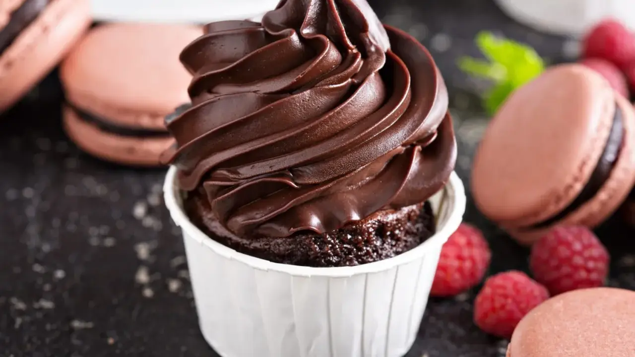 Gourmandise chocolatée : un cupcake avec ganache montée, macarons et framboises. Idéal pour la conservation ganache montée frigo.